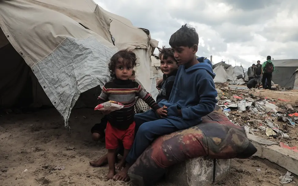 Gaza Hunger: Drei Kinder sitzen vor einem provisorischem Zelt