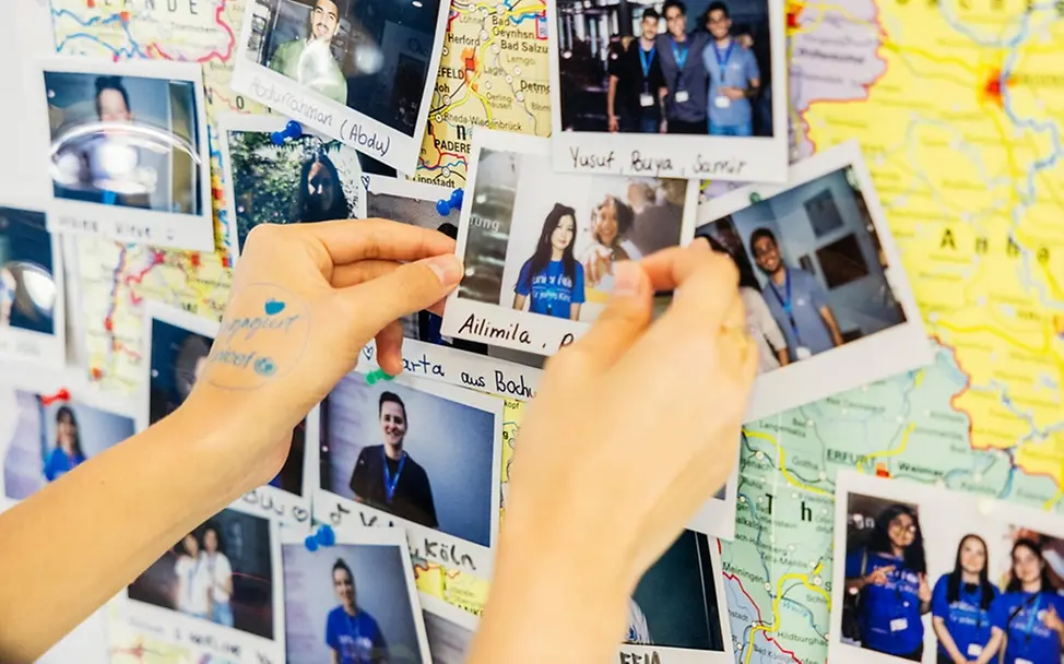 Was ist Demokratie einfach erklärt: Jugendliche pinnen Fotos auf eine Karte von Deutschland 