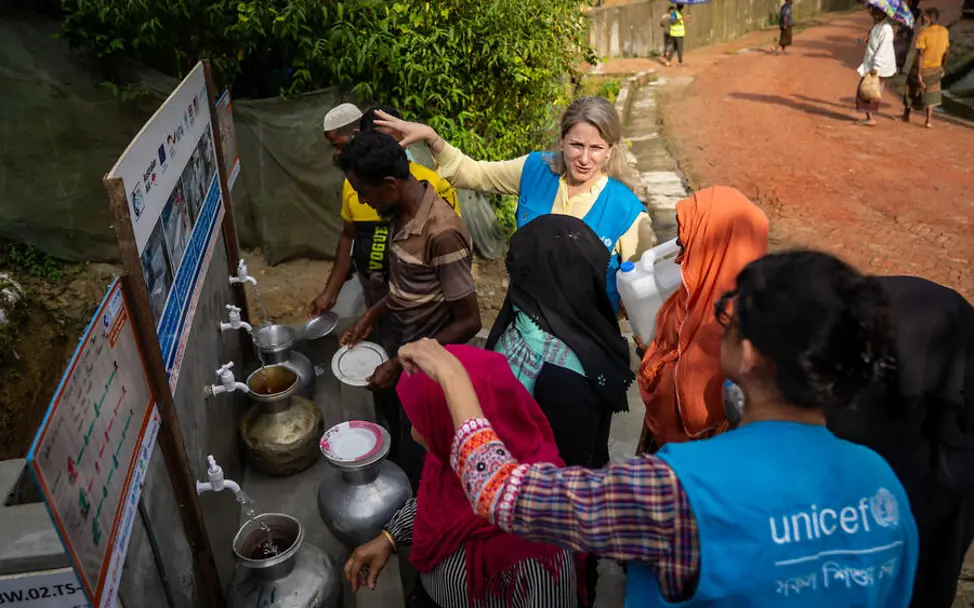 Rohingya Flüchtlingslager: UNICEF-Helfer*innen zeigen Rohingya die Wasserversorgung im Flüchtlingscamp. 