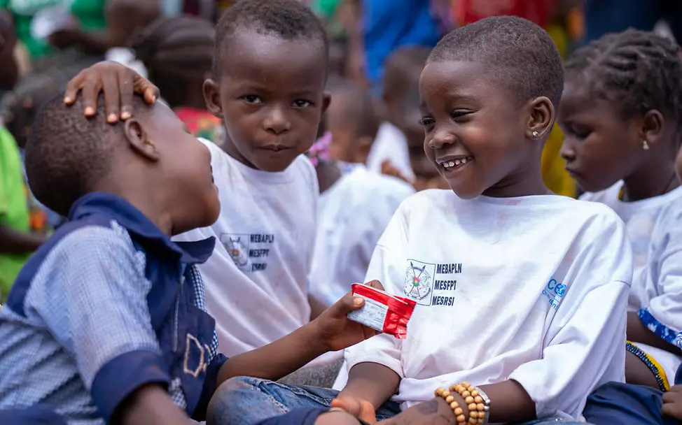 Kinderrechte leicht erklärt: Drei kleine Jungen sitzen lachend zusammen.