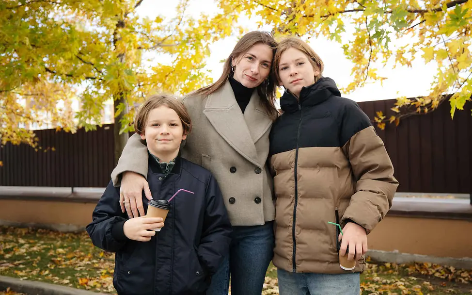 Menschenrechte einfach erklärt: Eine Mutter steht mit ihren Kindern vor herbstlichen Bäumen.