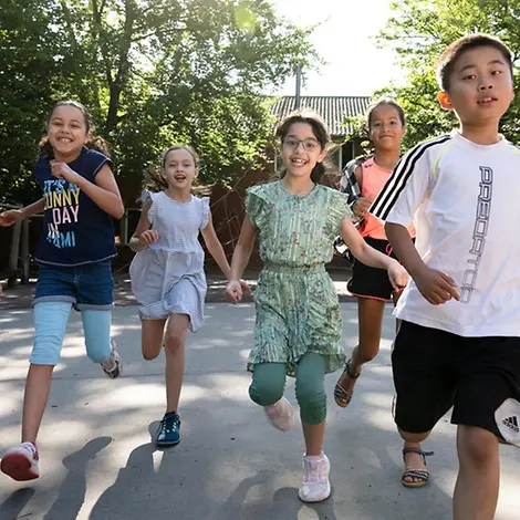 Menschenrechte einfach erklärt: Kinder laufen lachend auf einem Schulhof.