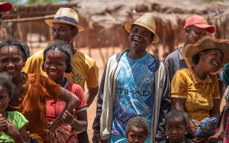 Menschenrechte einfach erklärt: Erwachsene und Kinder stehen lachend in einer Gruppe zusammen.