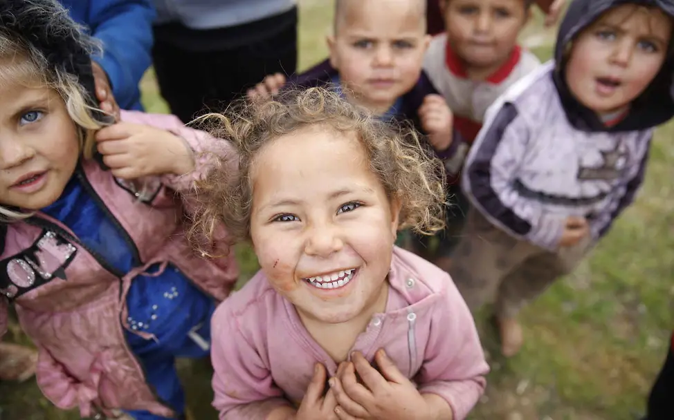 Menschenrechte einfach erklärt: Kinder blicken lachend in die Kamera.