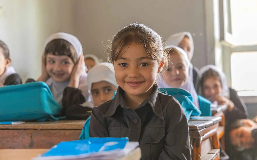 Menschenrechte einfach erklärt: Mädchen sitzen in ihrer Klasse an Schultischen