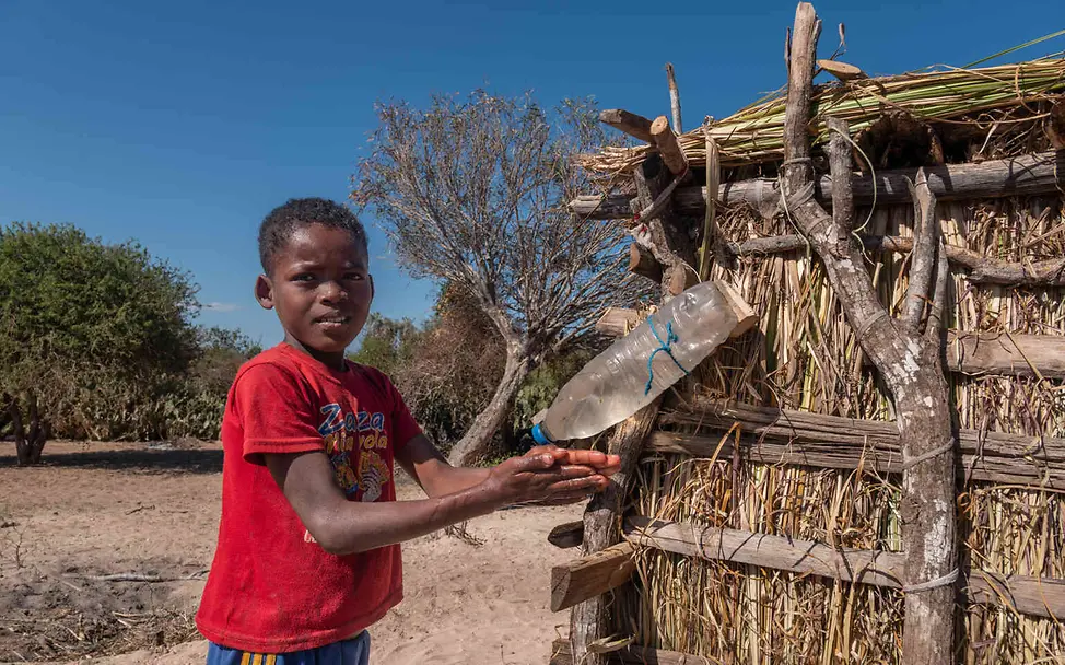 Madagaskar Hungerkrise: Ein Junge wäscht sich vor einer Latrine die Hände mit einer Wasserflasche.