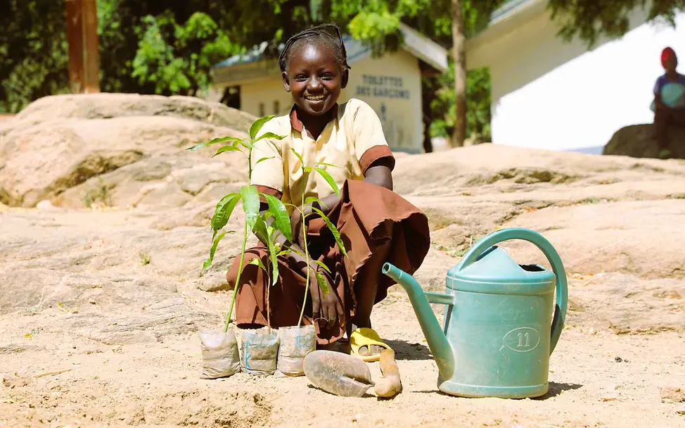 Klimaschutz einfach erklärt: Ein Mädchen mit Pflanzen und Gießkanne auf trockenem Boden.