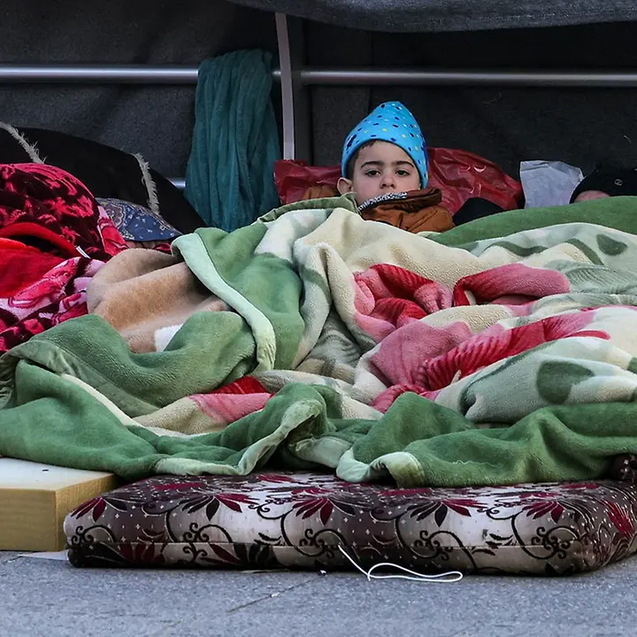Libanon spenden: Ein geflüchteter Junge im südlichen Libanon liegt unter einer Decke. 