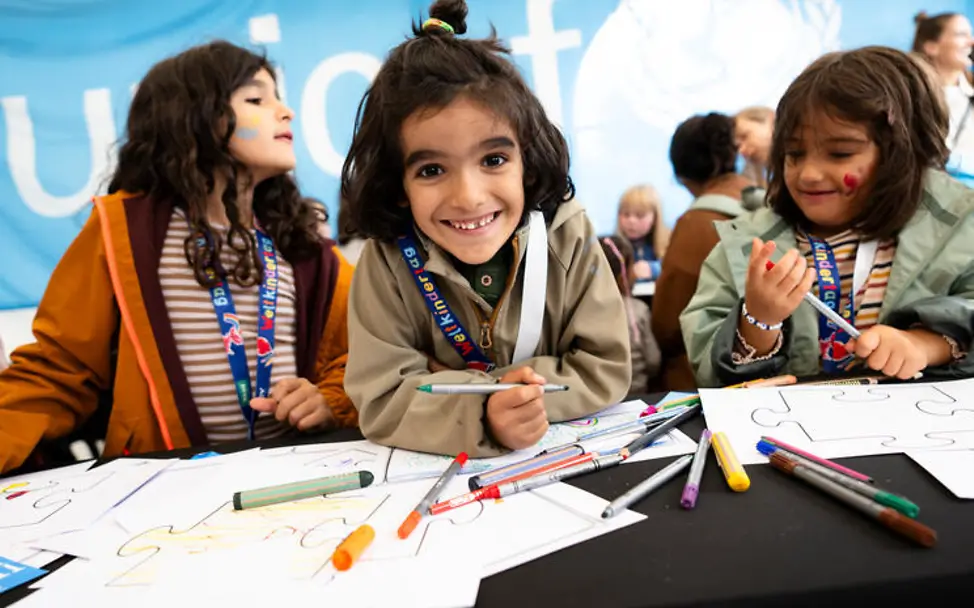 Weltkindertag einfach erklärt: Drei Mädchen an einem Maltisch
