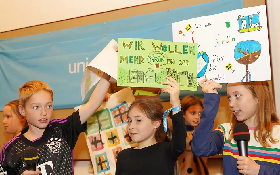 Weltkindertag einfach erklärt: Kinder zeigen ihre Plakate zum Weltkindertag.