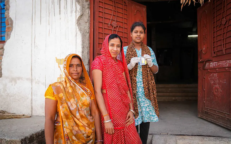 Wasserknappheit weltweit: Ein Mädchen und zwei Frauen zeigen einen Feldtest für Trinkwasser.
