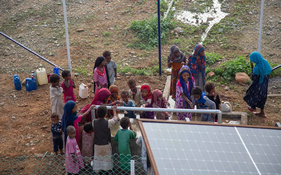 Wasserknappheit weltweit: Menschen stehen um eine solarbetriebene Wasserpumpe.