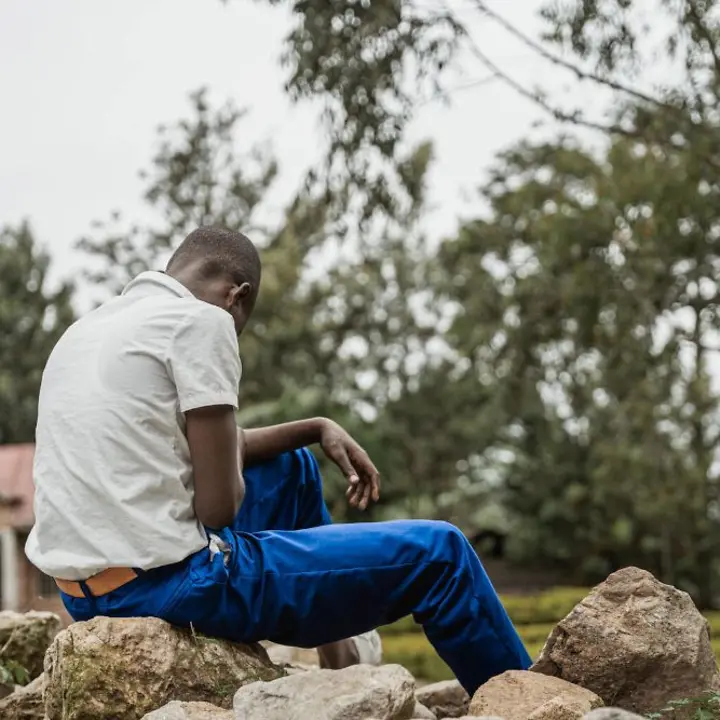 Kindersoldaten im Kongo: Ein Junge sitzt mit dem Rücken zur Kamera auf einem Stein.