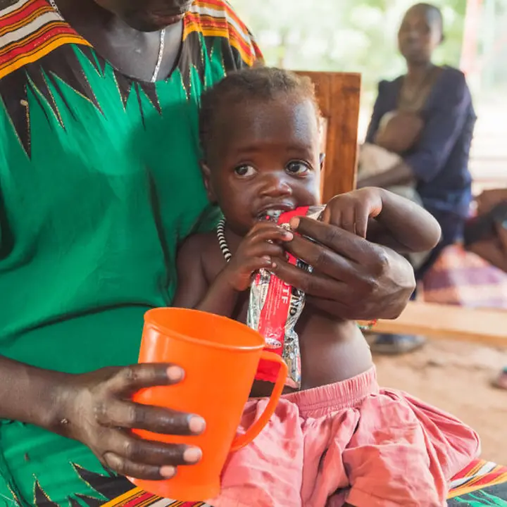 Hungerkrise in Kenia: Hunderttausende Kinder im Land sind mangelernährt. | © UNICEF/Kidero Hunger in Kenia: Ein Kleinkind auf dem Schoß seiner Mutter wird mit Erdnusspaste gefüttert.