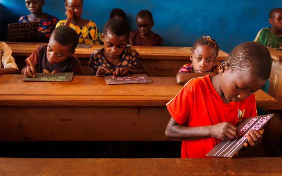 Zentralafrikanische Republik Hungerkrise: UNICEF unterstützt den Bau und die Wiedereröffnung von Schulen, damit Kinder lernen können. | © UNICEF/Vigné Hunger in der Zentralafrikanischen Republik: Ein Junge schreibt im Klassenzimmer auf seine Schultafel.