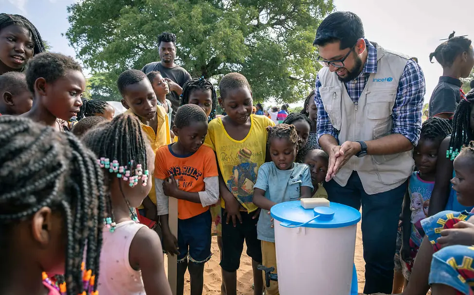 Eine hygienische Grundversorgung und sauberes Wasser können Krankheitsausbrüche verhindern | © UNICEF/Silva Mosambik Überschwemmungen: Ein UNICEF-Helfer wäscht gemeinsam mit Kindern die Hände.