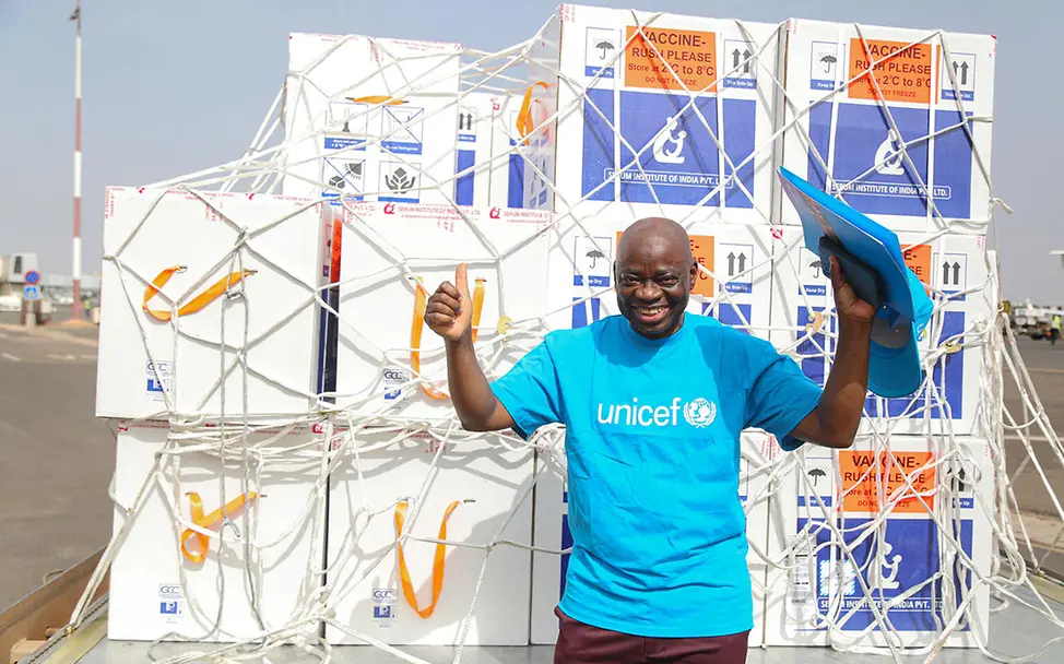 Ein UNICEF-Mitarbeiter steht strahlend vor großen Kartons mit Malaria-Impfstoffen. | © UNICEF/Keïta Malaria: Ein UNICEF-Mitarbeiter in Mali freut sich über die Ankunft von Malaria-Impfstoffen.