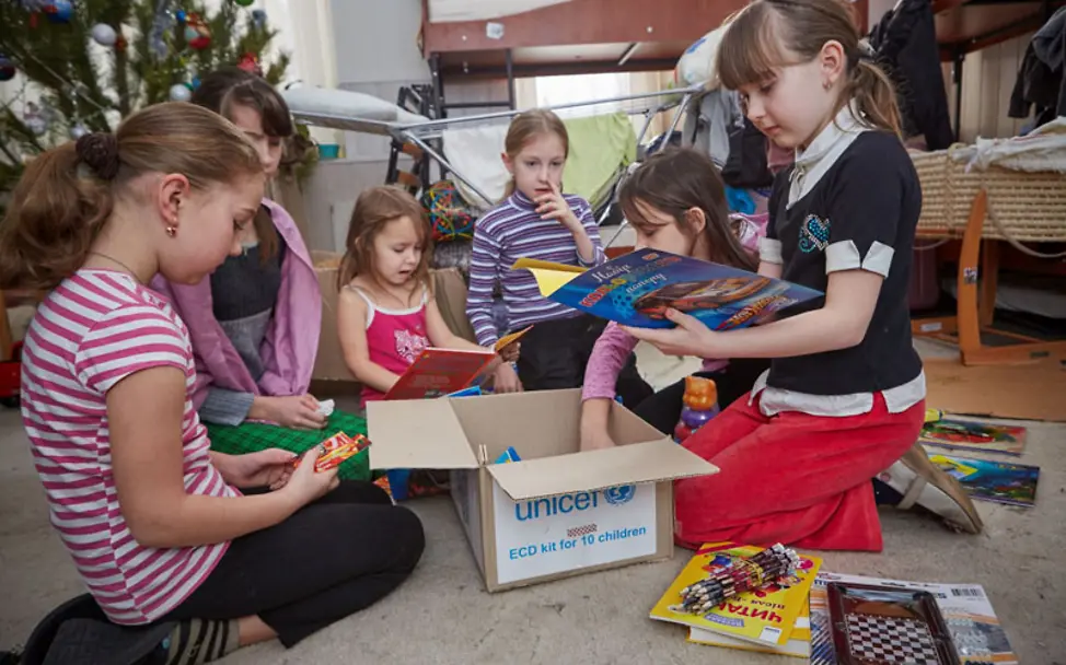 Kinder in der Ost-Ukraine packen einen UNICEF-Karton mit Büchern und Spielzeugen aus. Ukraine-Krise: Lernmaterial und Spielzeug für Kinder in der Ost-Ukraine.